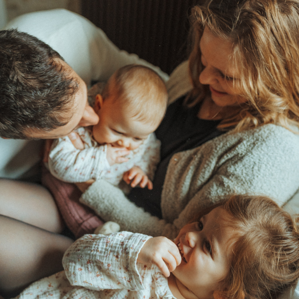 Famille qui s'enlace sur un lit.